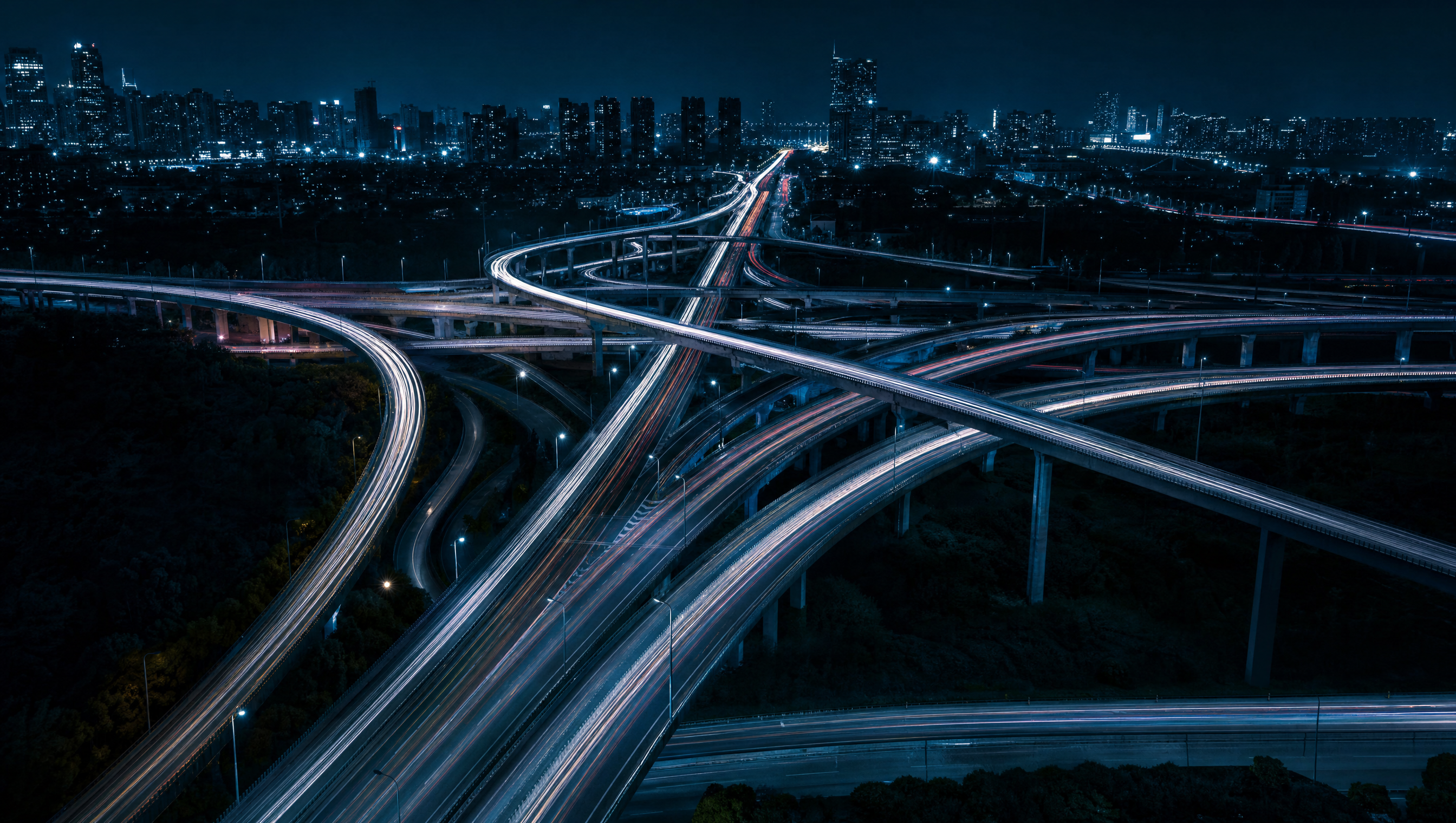 A highway interchange at night with streams of vehicle lights